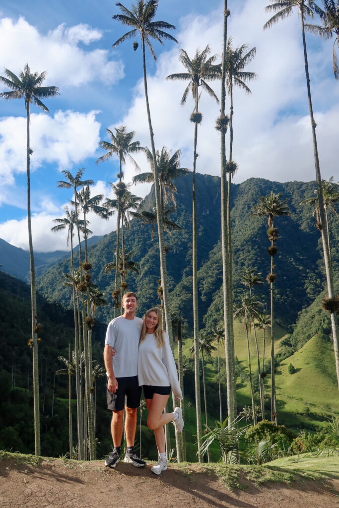Couple standing in front of towering wax palms in Cocora Valley, Colombia
