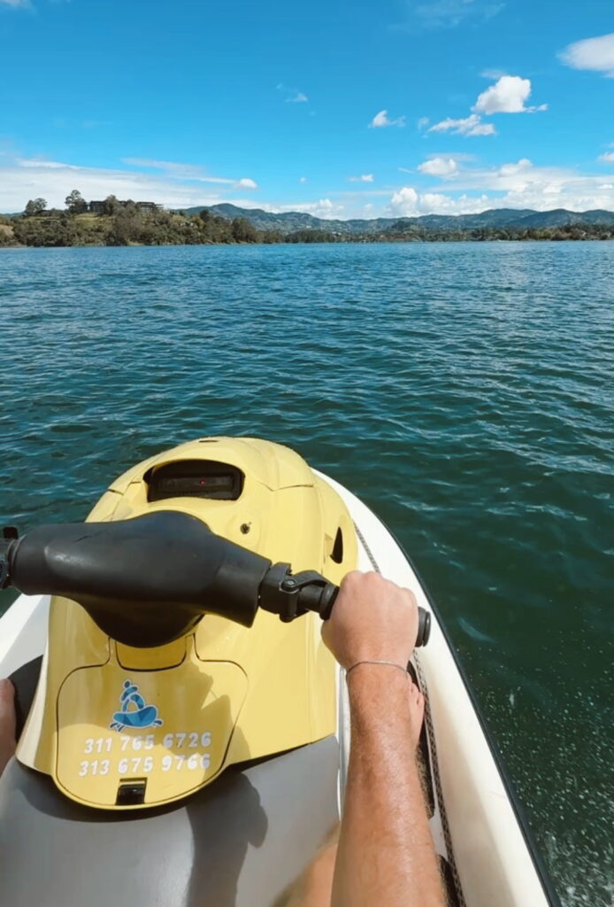 Jet skiing on Guatape Lake surrounded by green hills and blue water