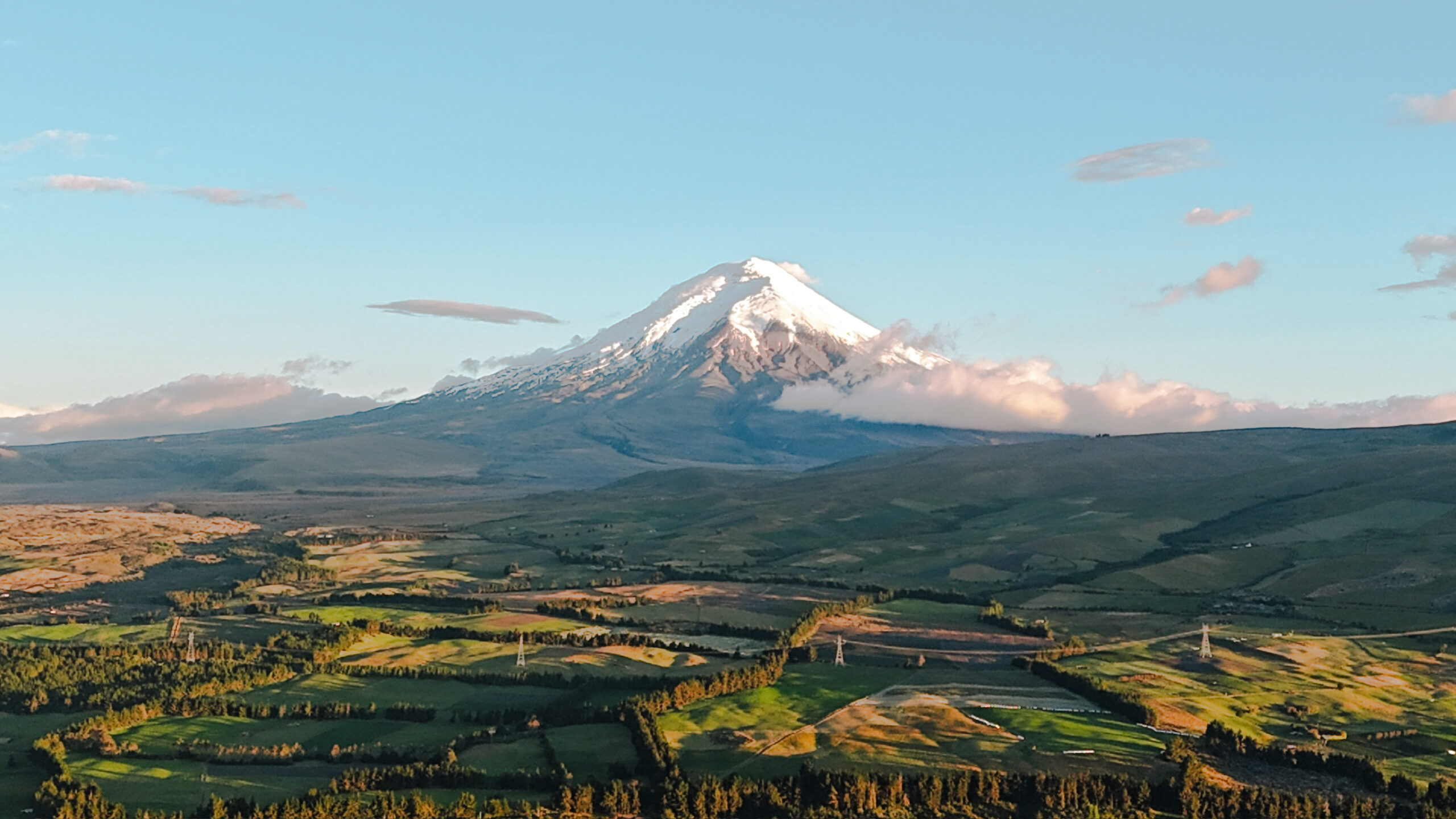 A high angle bird's eye drone view looking straight down toward the massive snow covered symmetrical peak of the active volcano. Photo taken at the Secret garden Cotopaxi hostel in Ecuador.