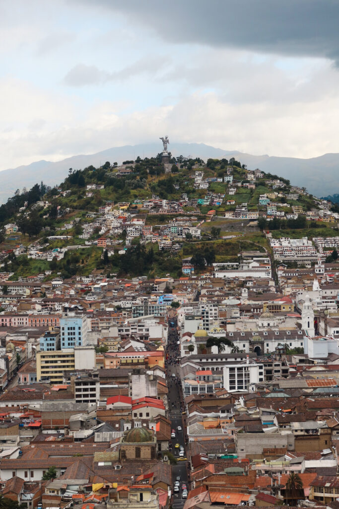 A telephoto zoomed in view looking toward the prominent El Panecillo hill in Quito with the giant aluminum statue of the Virgin Mary standing on top.