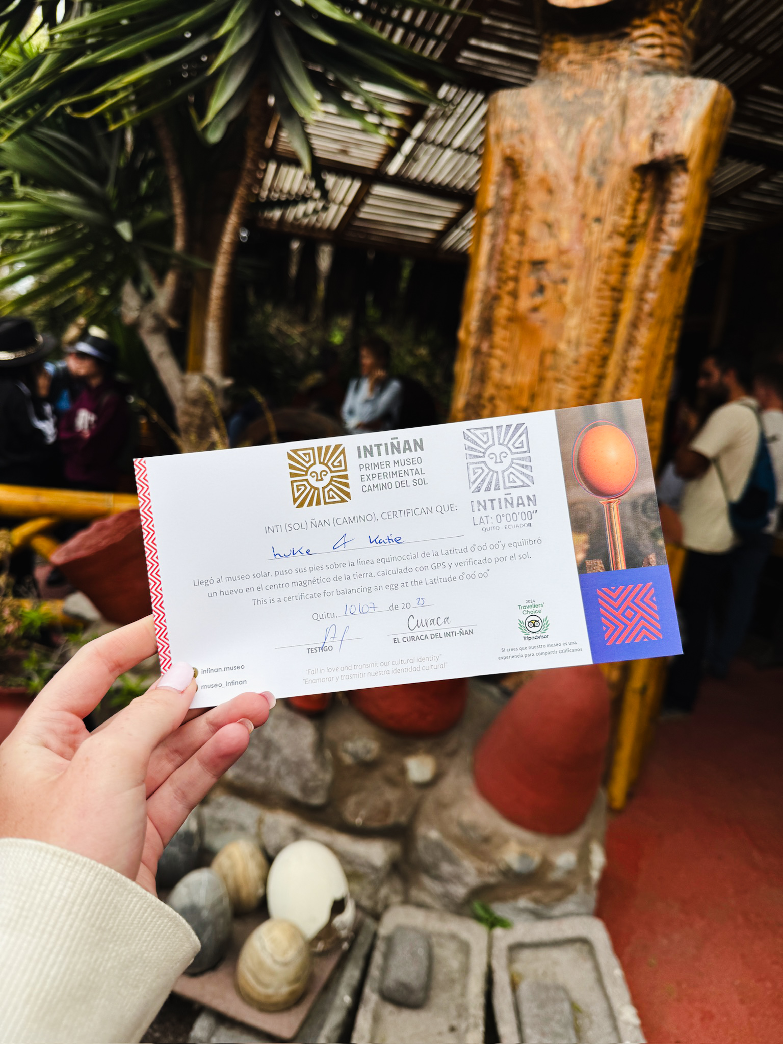 A hand holding up an official certificate for successfully balancing an egg on the head of a nail at the equator.
