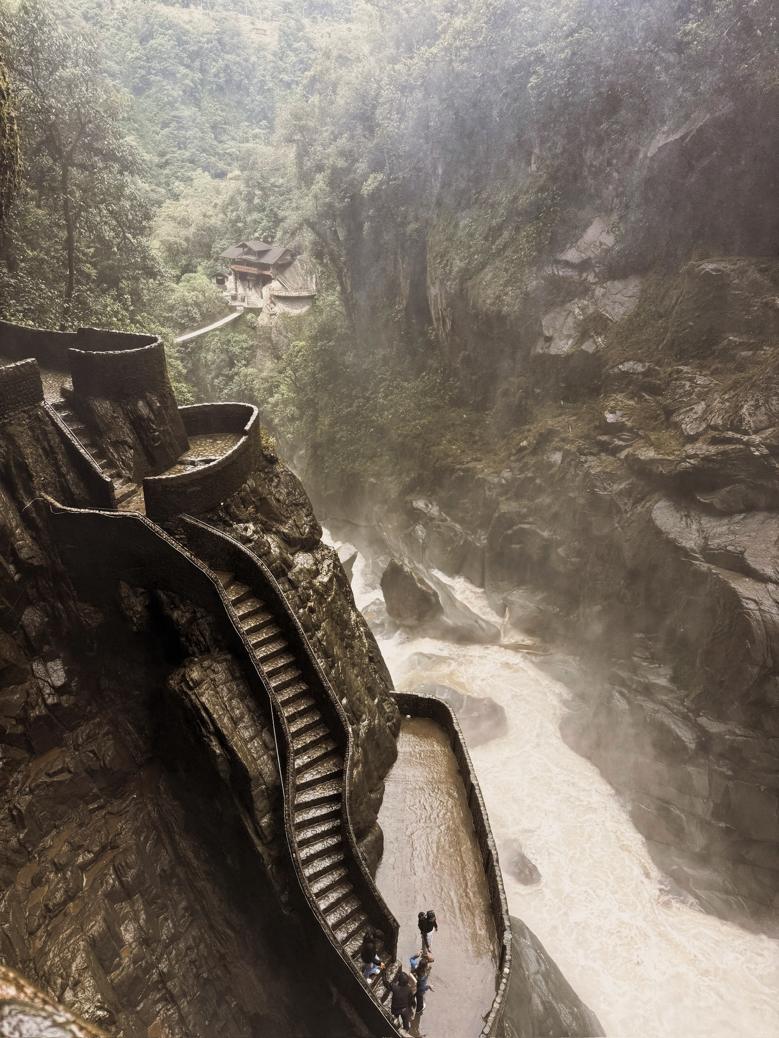 A powerful, massive waterfall cascading into a rocky canyon gorge in Banos, Ecuador.