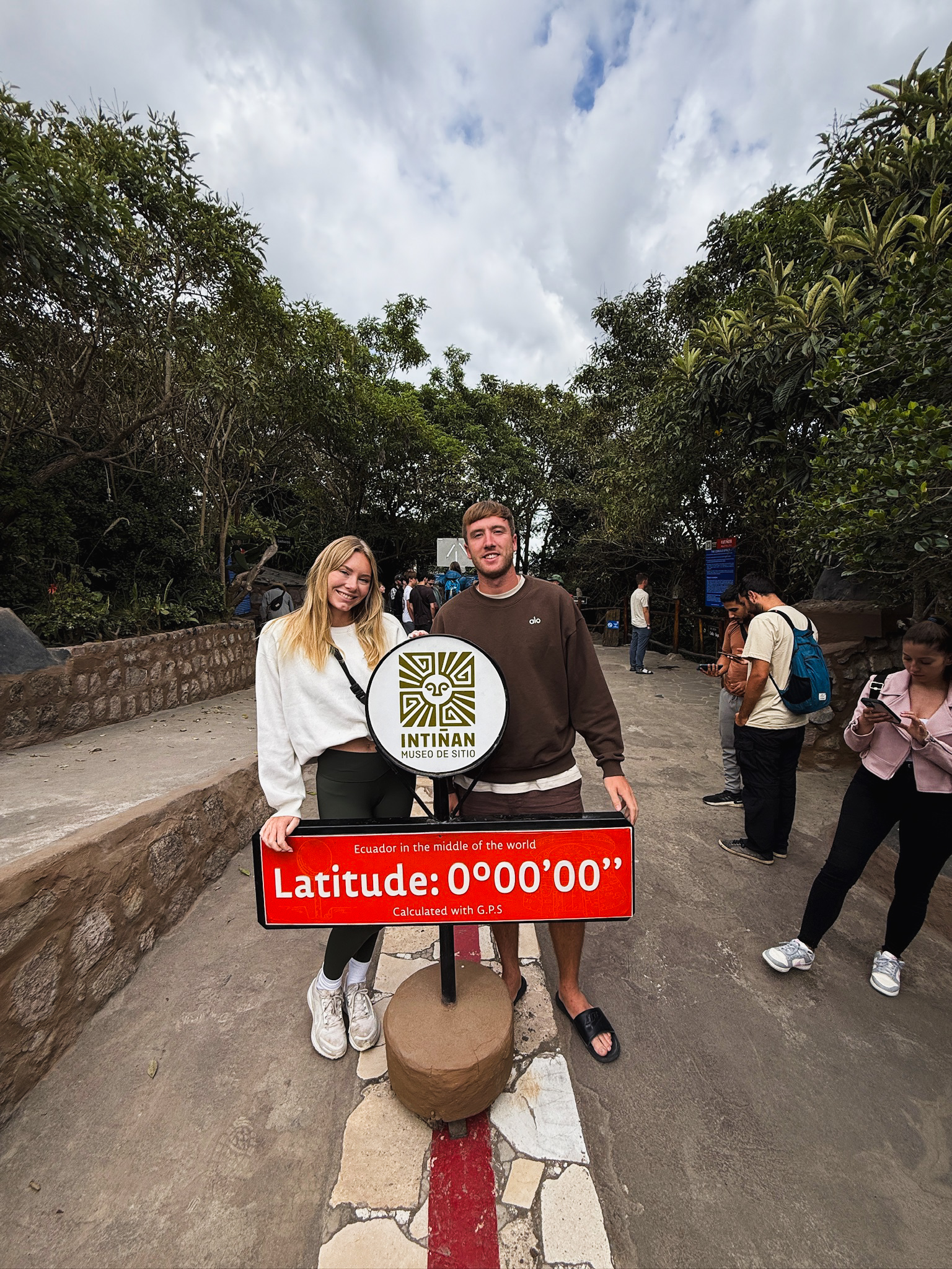 Me and Luke posing next to the official latitude 0.00.00 equator line marker during a day trip from Quito. Quito Travel Guide Must do!